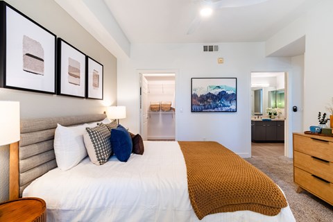 A bedroom with a large bed and a painting on the wall.