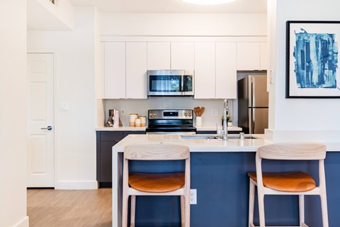 A kitchen with white cabinets and a blue backsplash.