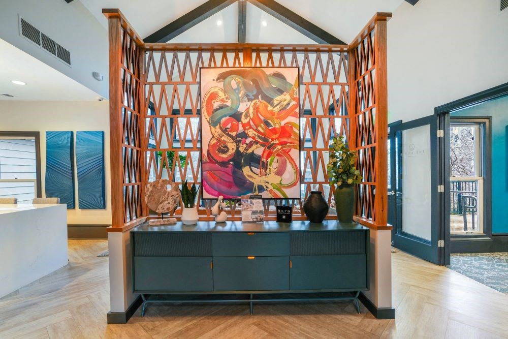 A large painting hangs on a wooden frame in a spacious room.