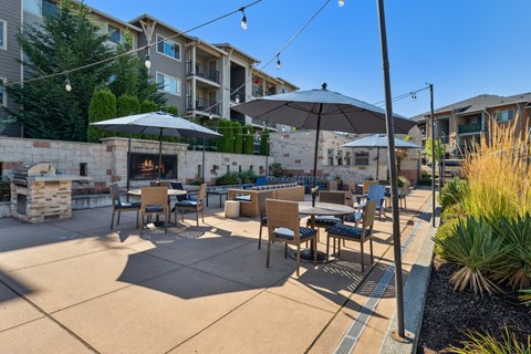 an outdoor patio with tables and umbrellas and a fireplace