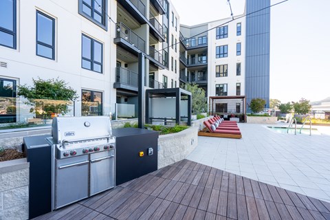 an outdoor patio with a barbecue grill and a pool in front of an apartment building