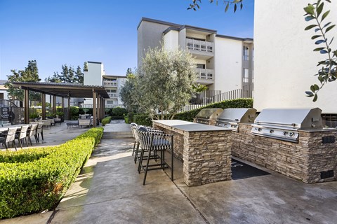 a patio with a barbecue grill and tables and chairs