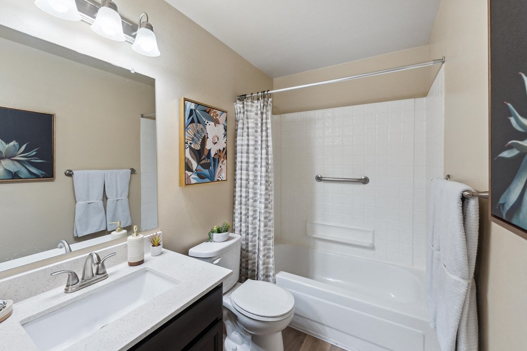 a bathroom with a white tub and shower and a sink