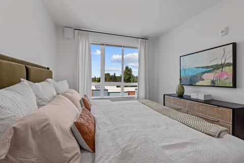 A bedroom with a large bed and a painting on the wall.