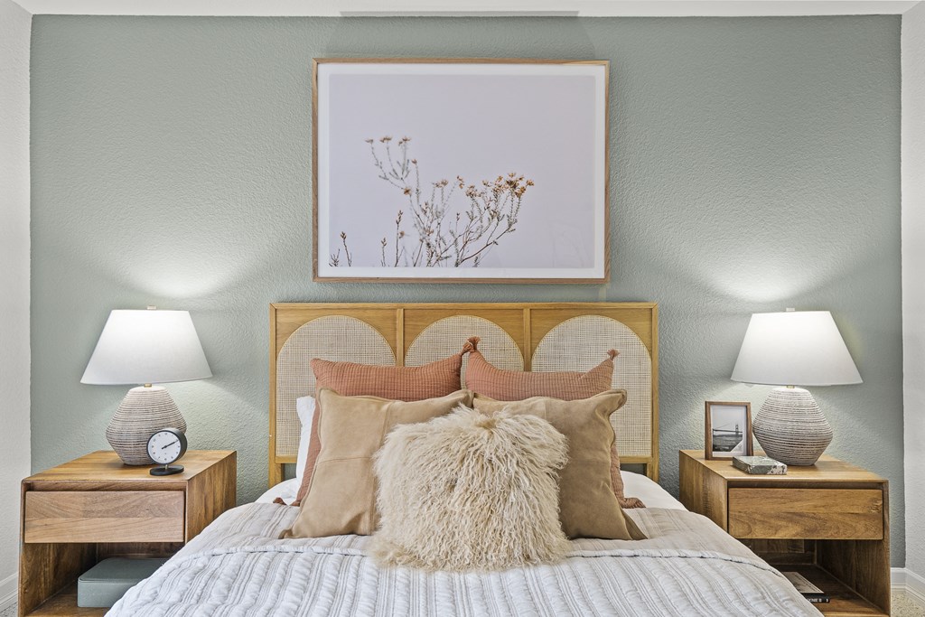 a bedroom with a bed with pillows and a picture above it