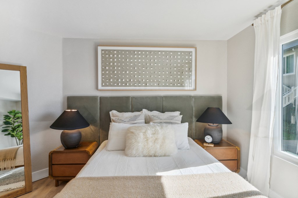 a bedroom with a bed and two lamps and a window