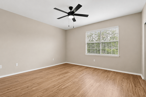 A room with a ceiling fan and a window with blinds.