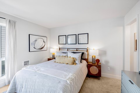 A bedroom with a large bed and a window with curtains.