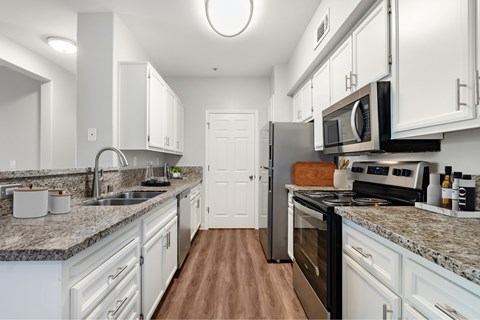 A kitchen with white cabinets and a black refrigerator.