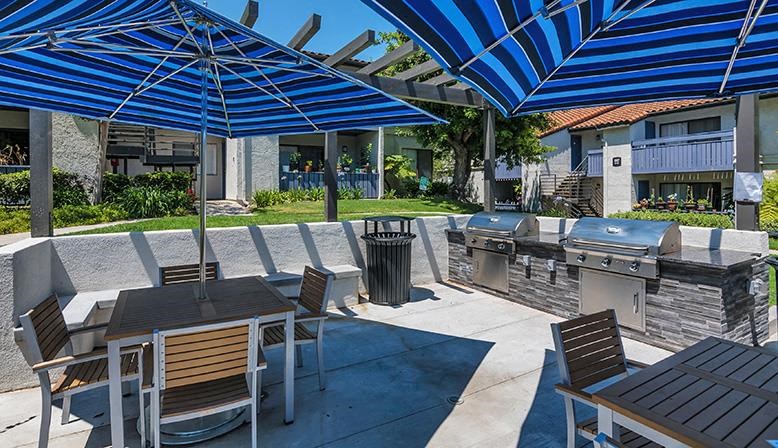 a patio with tables and umbrellas and a grill