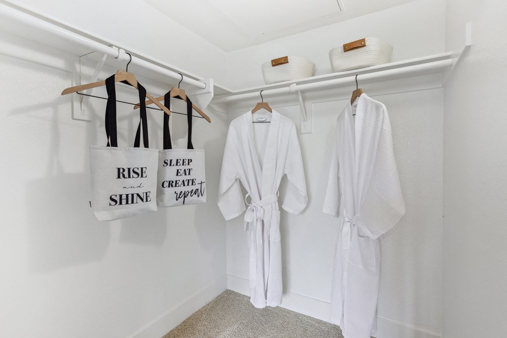 a spa room with white robes and accessories and bags on the wall