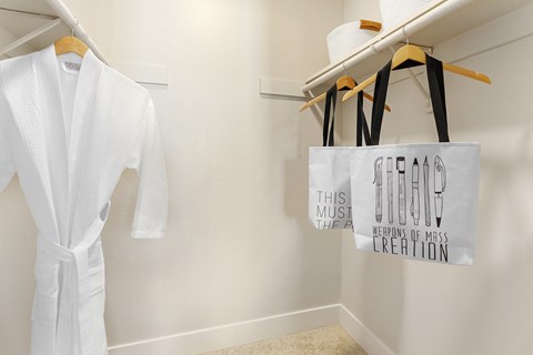 a closet with a white robe and a tote bag hanging on the wall