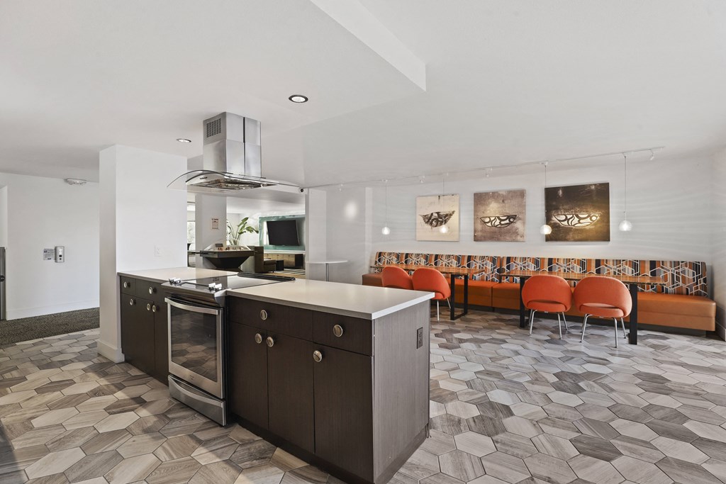 a kitchen with an island and a dining room with orange chairs