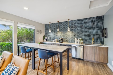 A modern kitchen in the clubhouse with a dining table and chairs.