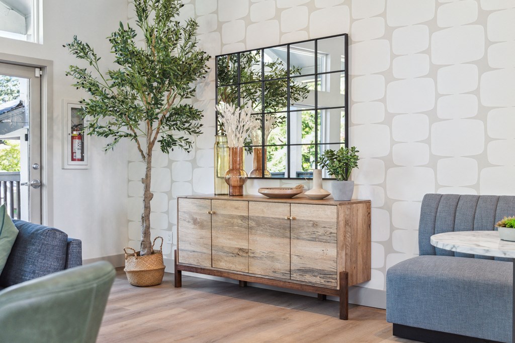 a living room with a dresser and plants and a mirror