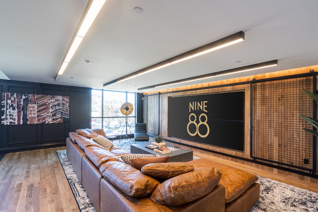 a living room with a brown couch and a large screen on the wall
