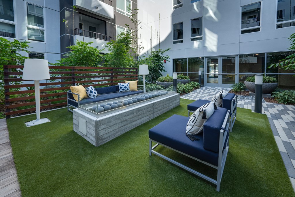 an outdoor lounge area with couches and pillows on grass