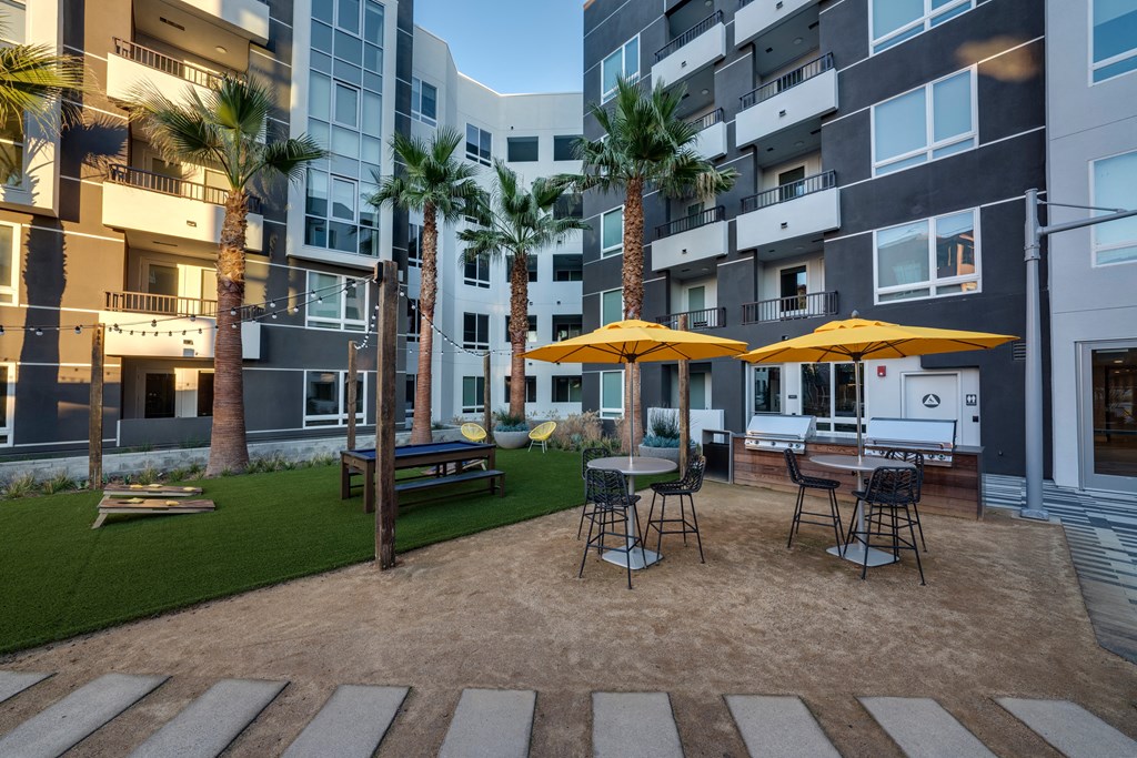 a patio with tables and umbrellas in front of an apartment building