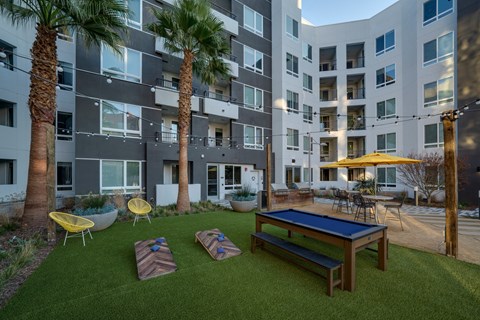 an outdoor amenities area with a ping pong table and an apartment building