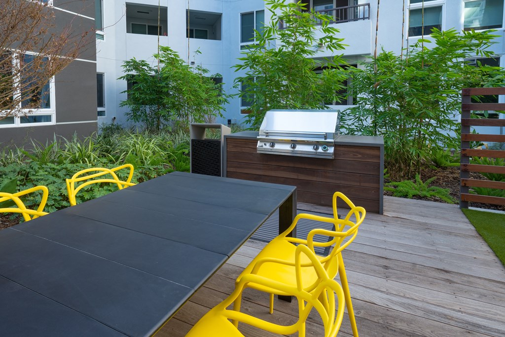 a patio with a table and chairs and a grill