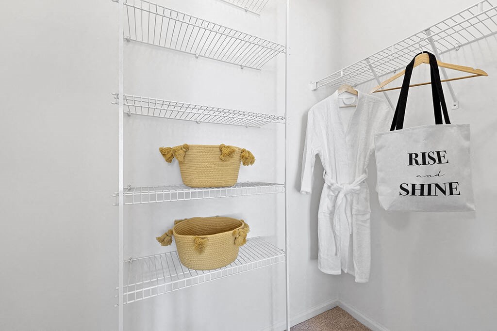 a white closet with a basket and a tote bag