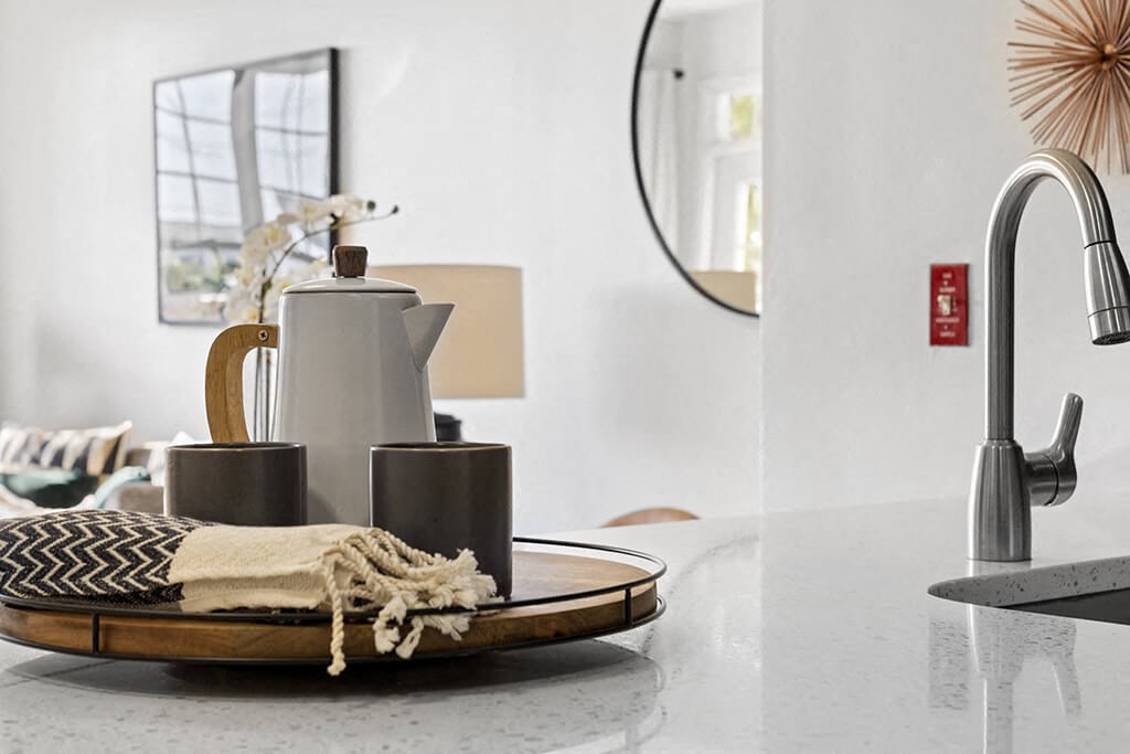 a kitchen counter with a tray with a coffee pot and a sink