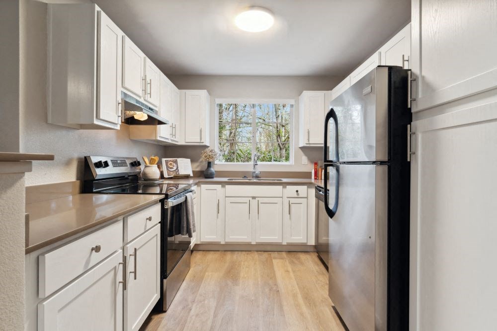 A kitchen with white cabinets and a black refrigerator.
