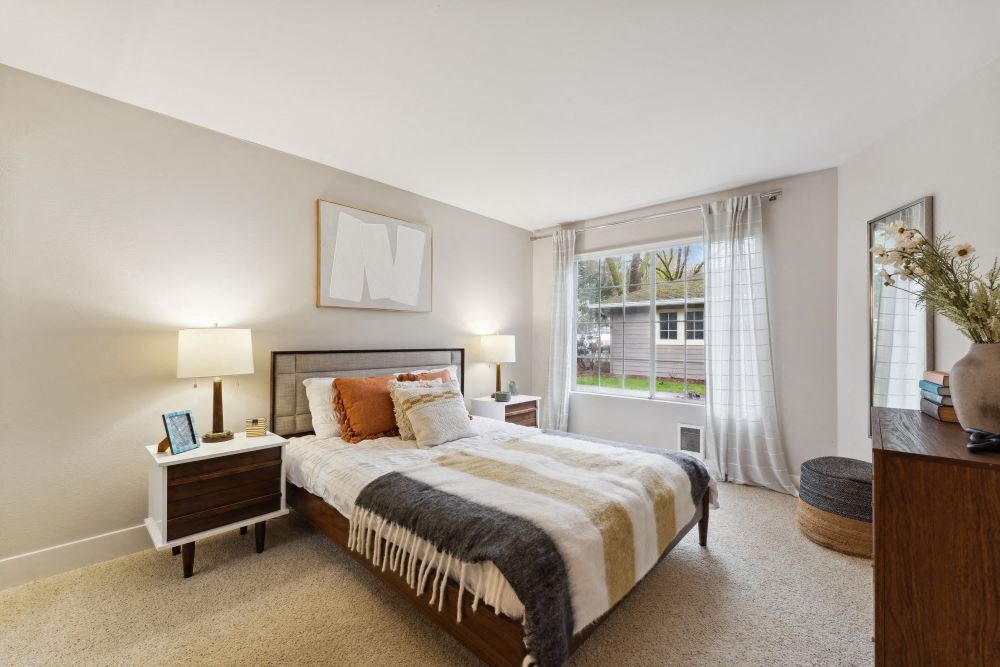 A bedroom with a large bed and a window with curtains.