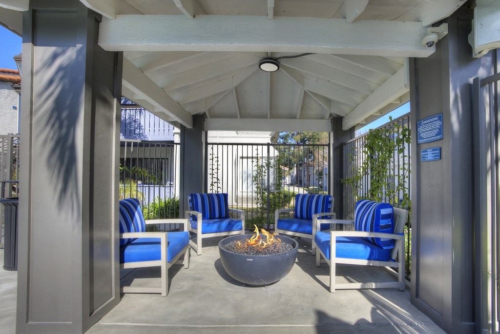 Sofi at Wood Ranch Apartments  covered patio with a fire pit and blue chairs