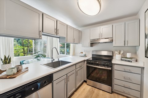 a kitchen with white cabinets and black appliances and a large window