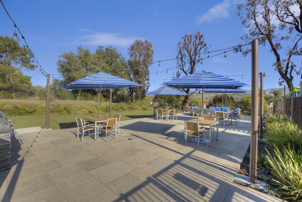 Sofi at Wood Ranch Apartments patio with tables and chairs and blue umbrellas