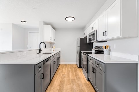 A kitchen with grey cabinets and appliances.
