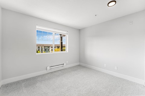 A room with a window showing a view of a building and trees.