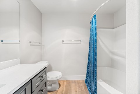A white bathroom with a blue shower curtain.