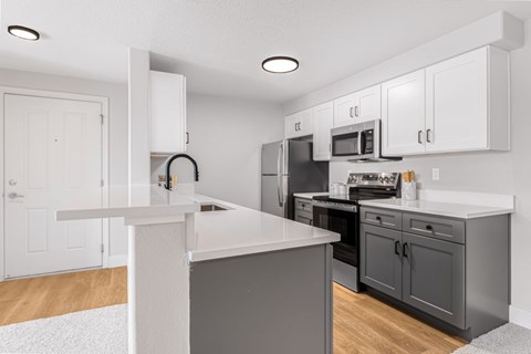 A kitchen with a white island and grey cabinets.