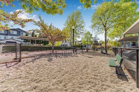 A playground with a green bench and a fence.