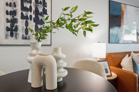 a table with vases and a plant in a living room