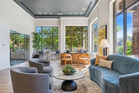 a living room with a blue couch and chairs and large windows