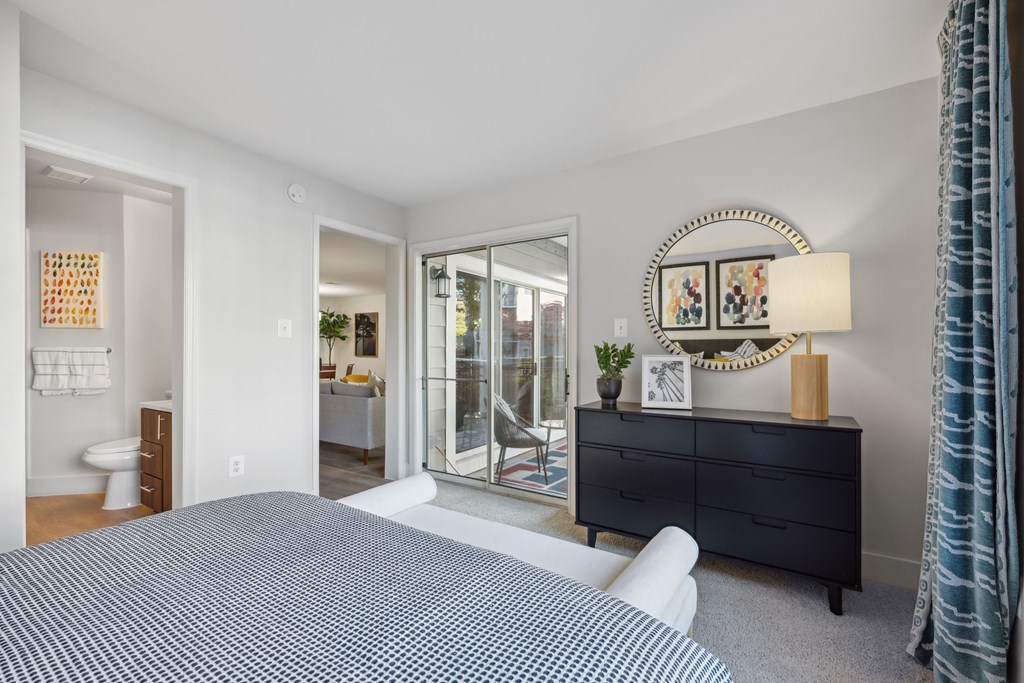 a bedroom with a bed and a mirror and a sliding glass door to a bathroom