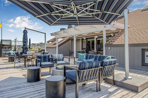 A patio with a striped couch and a striped umbrella.