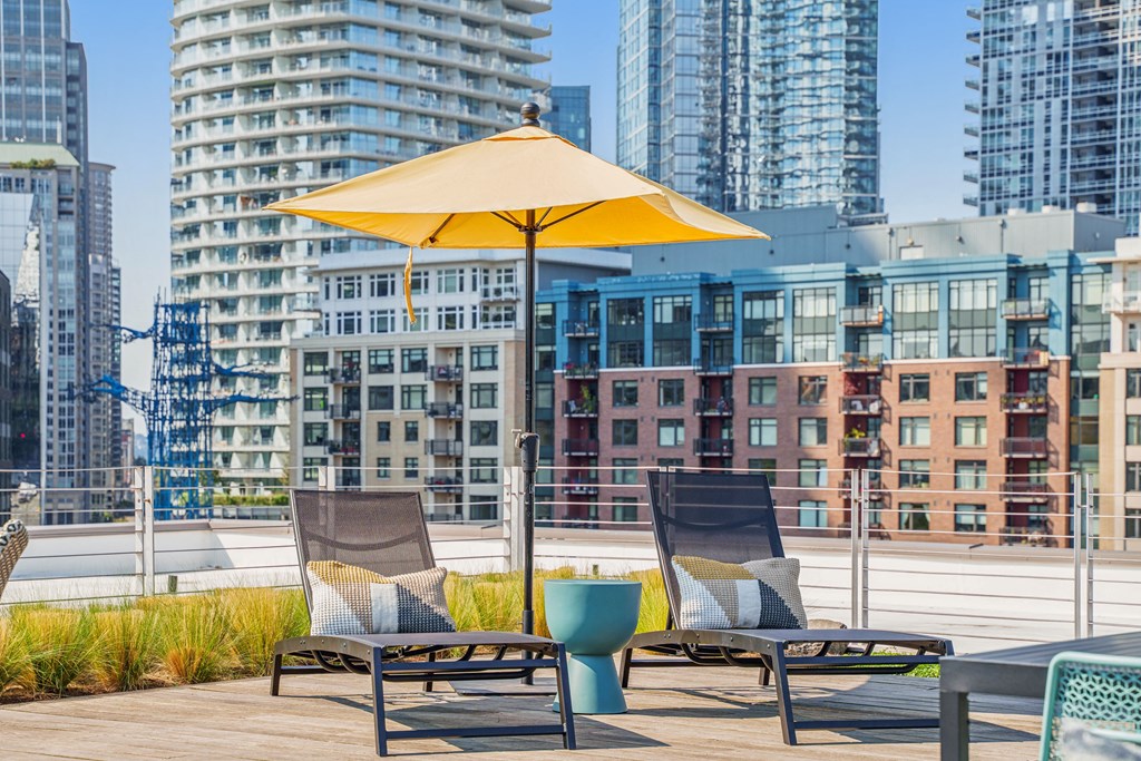 a patio with two chairs and an umbrella on a rooftop