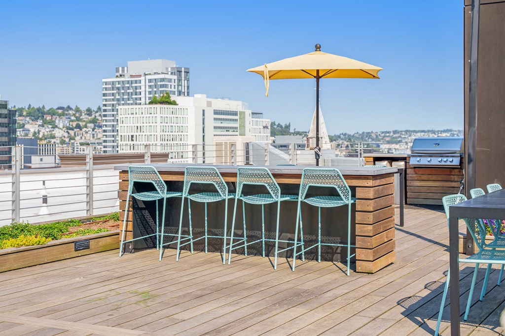 the deck has a bar with blue chairs and an umbrella on it