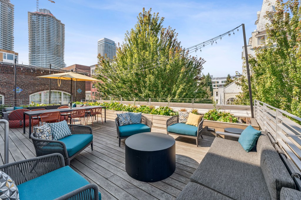 a rooftop patio with chairs and tables and a city in the background