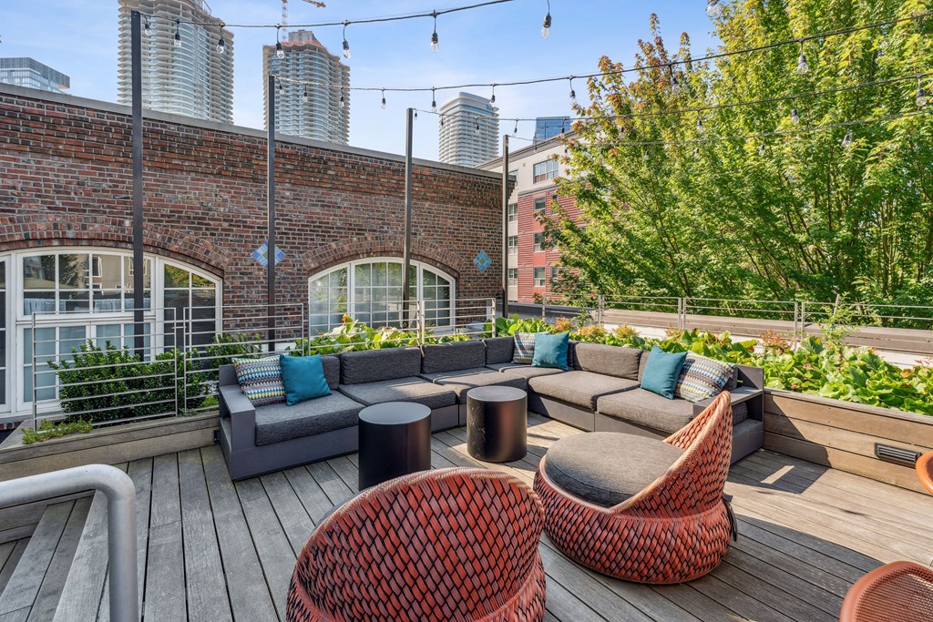 a rooftop patio with furniture and a city in the background