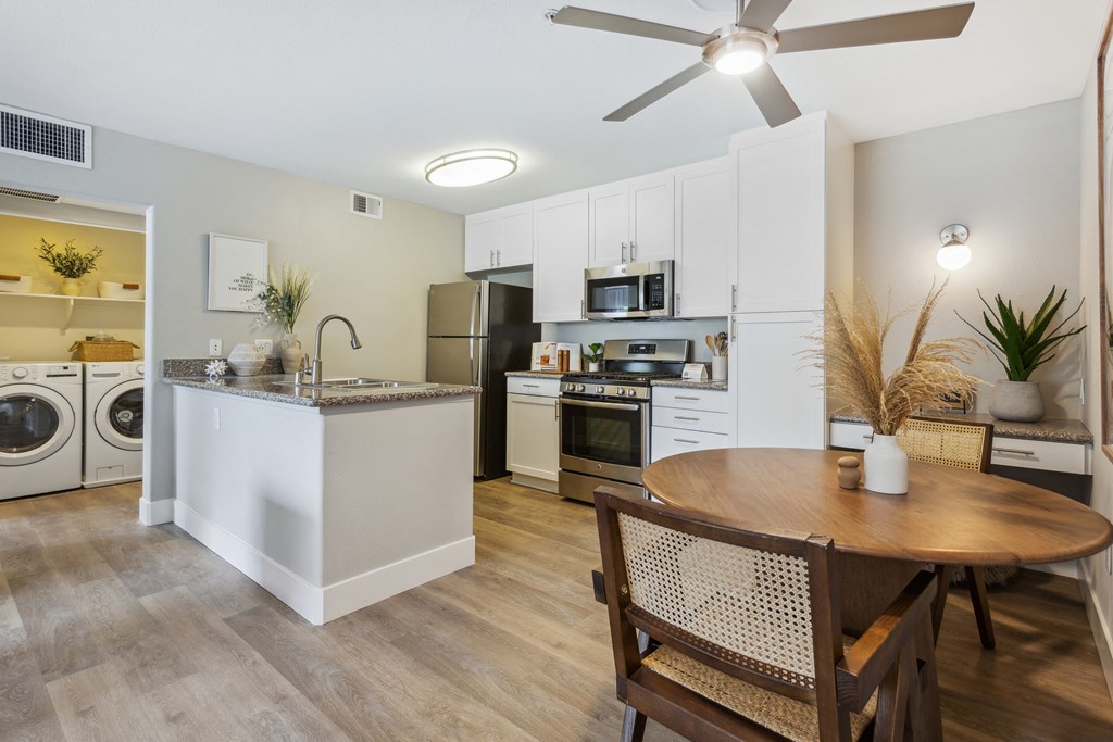 an open kitchen and dining area with a wooden table and chairs and a washing machine