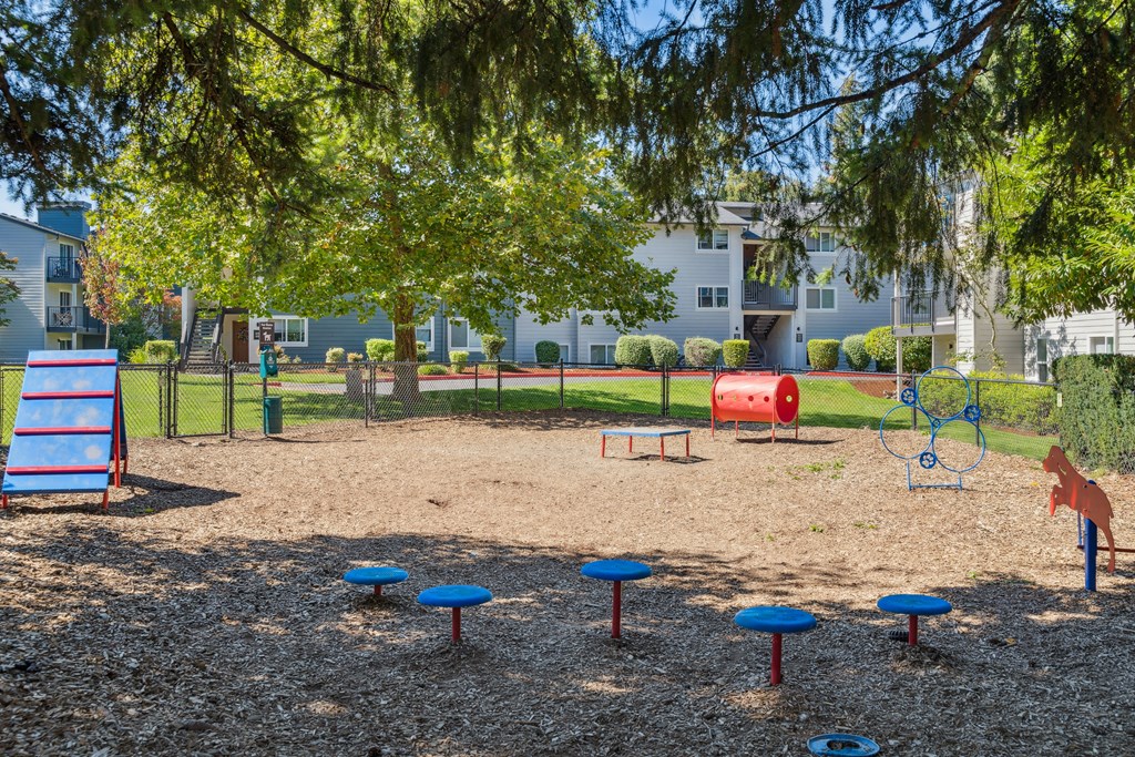 a playground with a tree and some playground equipment in front of a building