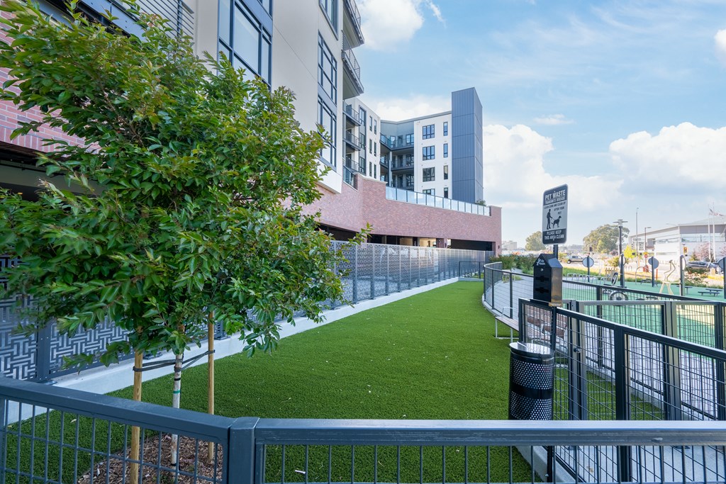 a grassy area in front of a building with a fence
