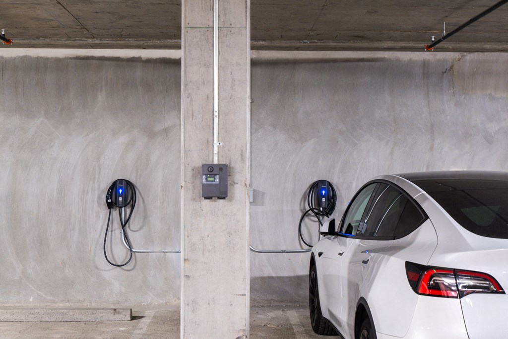 a white car is plugged into an electric charger in a parking garage