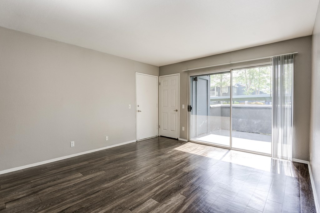 an empty living room with sliding glass doors to a patio