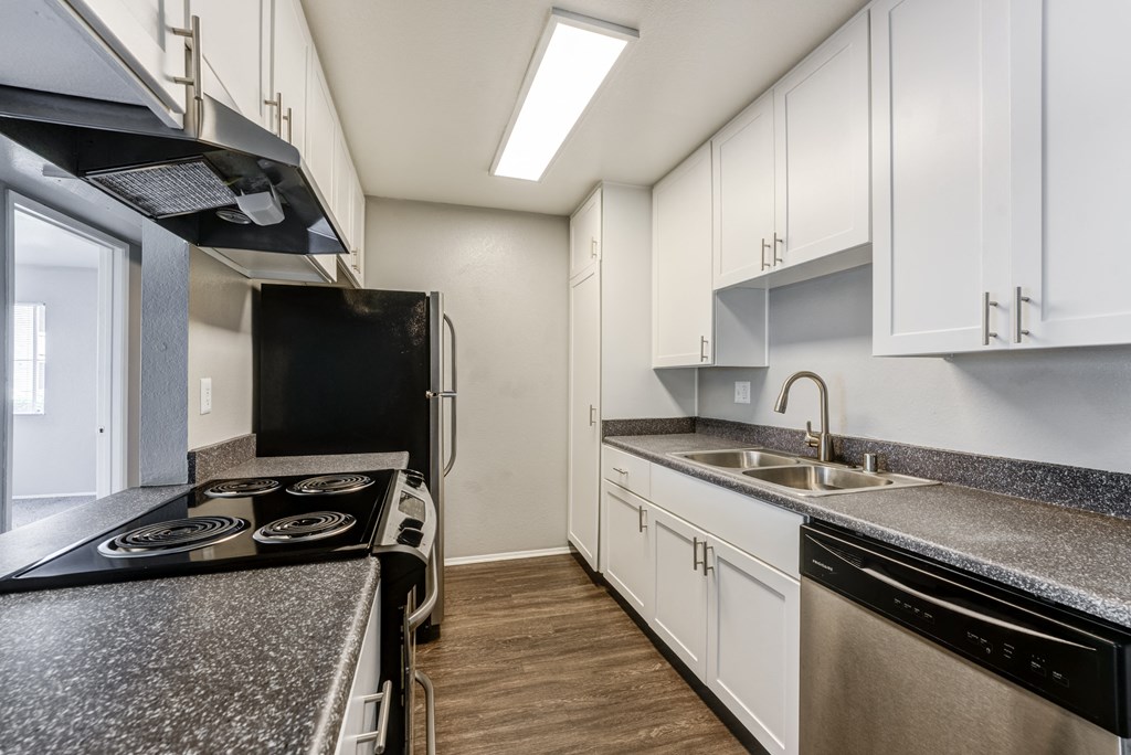 an empty kitchen with granite counter tops and white cabinets